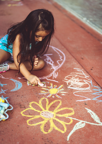 Cute tweenagers are drawing a hopscotch diagram in the schoolyard