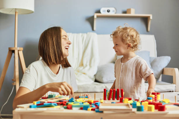 istock Imaginative storytelling games. Parental guidance time. Educational toy sets. Creative art projects. teacher or mother playing with baby with logical toys at home interior 1576637471