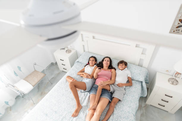 a family uses the remote to activate the electric ceiling fan, view from above Mother and children at hone conecting ceiling fan air conditioner family stock pictures, royalty-free photos & images
