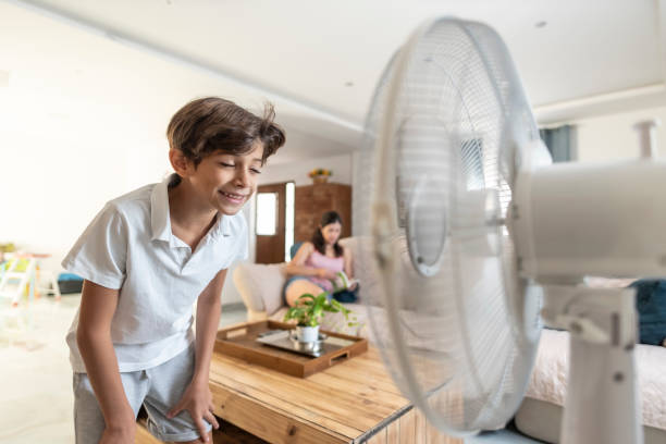 istock Children cool off with electric fan at home, refreshing face 1576655702