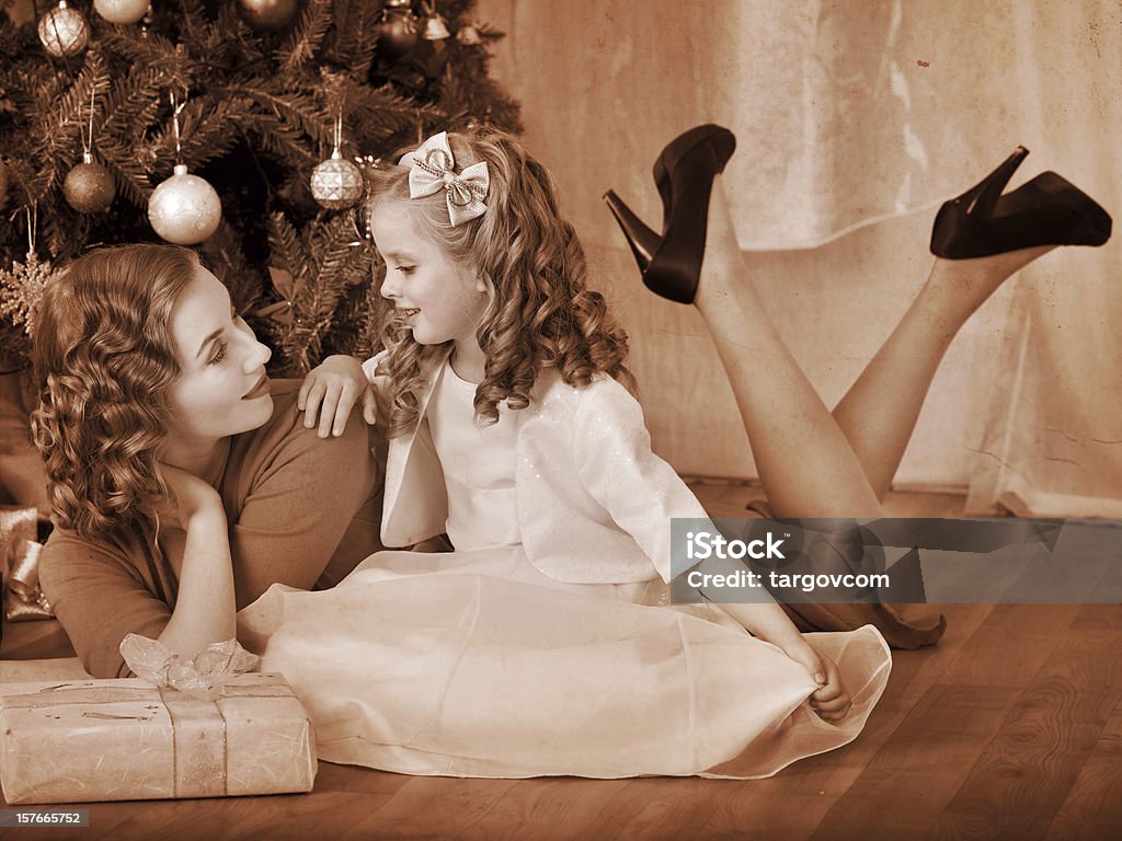Kid with mother near Christmas tree. Child with mother receiving near Christmas tree. Black and white retro. Adult Stock Photo