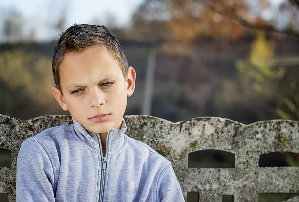 istock Sad child looking down, outdoors with a forest in background, 157666760
