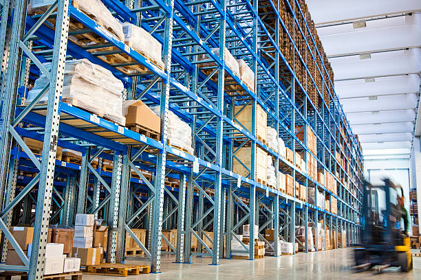 Forklift driving past blue industrial storage racks stock photo