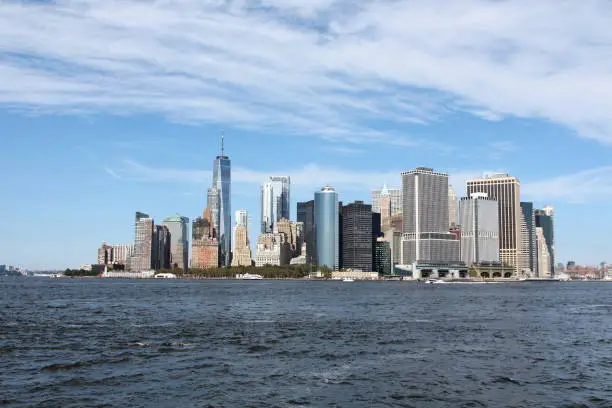 view of downtown manhattan new york city from governor's island in the hudson river (skyline with skycrapers including the freedom tower, water, sky)