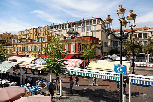 Nice, France - April 21, 2023: The famous market on Cours Saleya with visible striped roofs hiding the stalls from the sun. The buildings of the city are visible a little further.