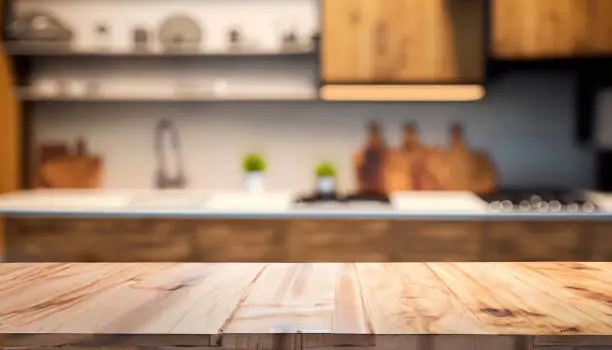 Empty wooden table and blurred modern kitchen background provide an excellent setup for product display. Creates a sleek and professional ambiance to showcase items effectively.