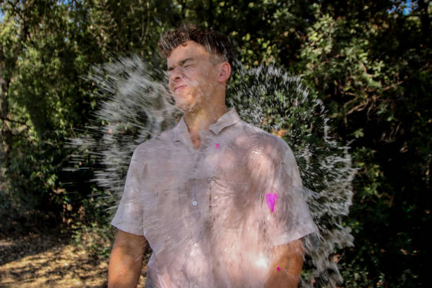 Young man wet at the park Man soaked with a water ballon at the park water balloon stock pictures, royalty-free photos & images