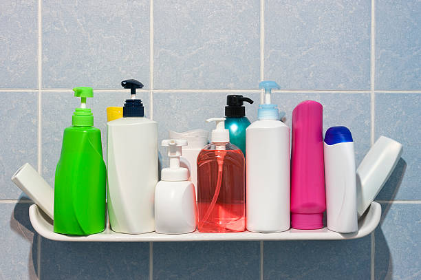 Many shampoo and soap bottles on a bathroom shelf. stock photo