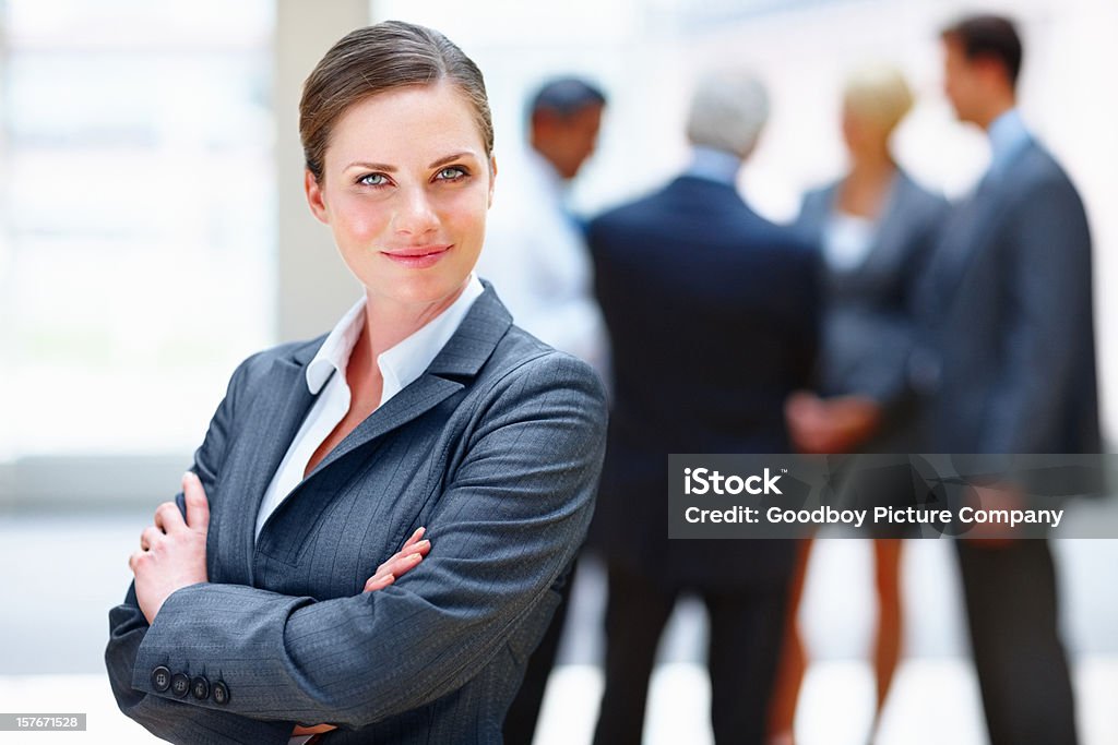 Счастливый бизнес женщина улыбается с коллегами в фоновом режиме - Стоковые фото Администратор роялти-фри