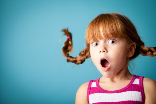 Whimsical, color photo of a red-haired girl with upward braids and a look of surprise!