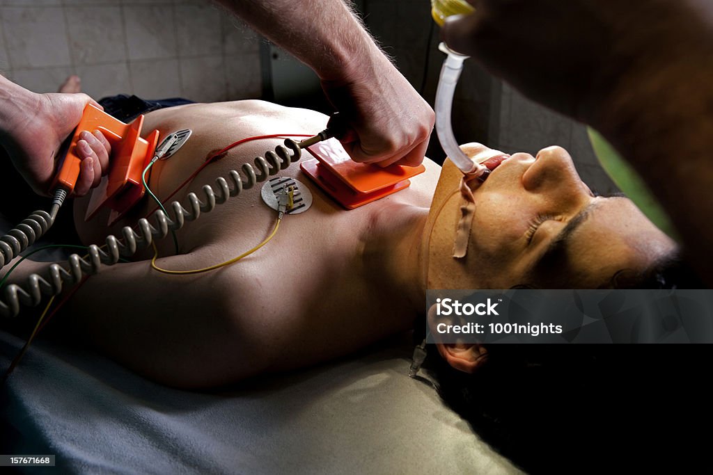Doctors at ER Doctor is using defibrillator on his patient. Accidents and Disasters Stock Photo