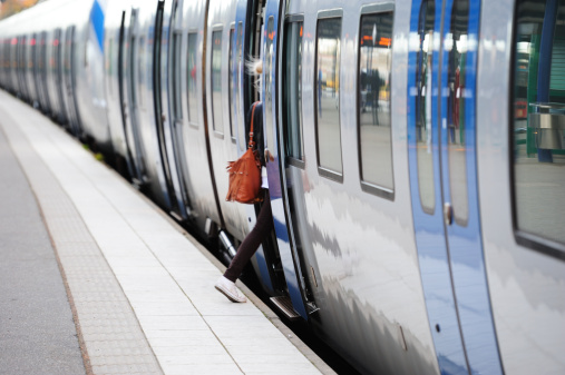 Girl with hand bag entering train or underground carriage in bright summer daylight. Motion blur in direct sunligt. Diminishing perspective. Doors are blue and open.