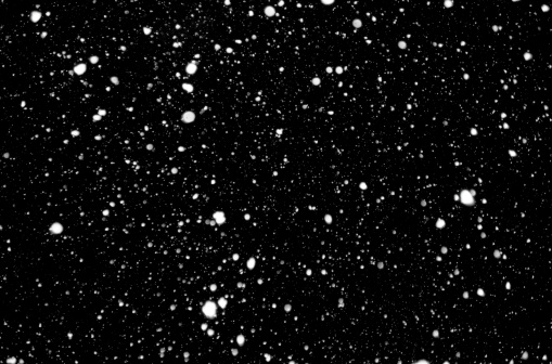 Snowflakes against black night sky.