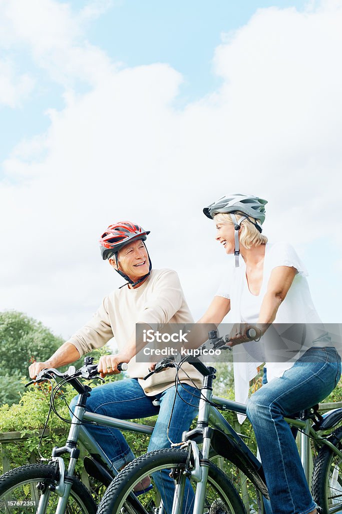 Maduro feliz hombre y mujer en ciclo paseo en campo - Foto de stock de Andar en bicicleta libre de derechos