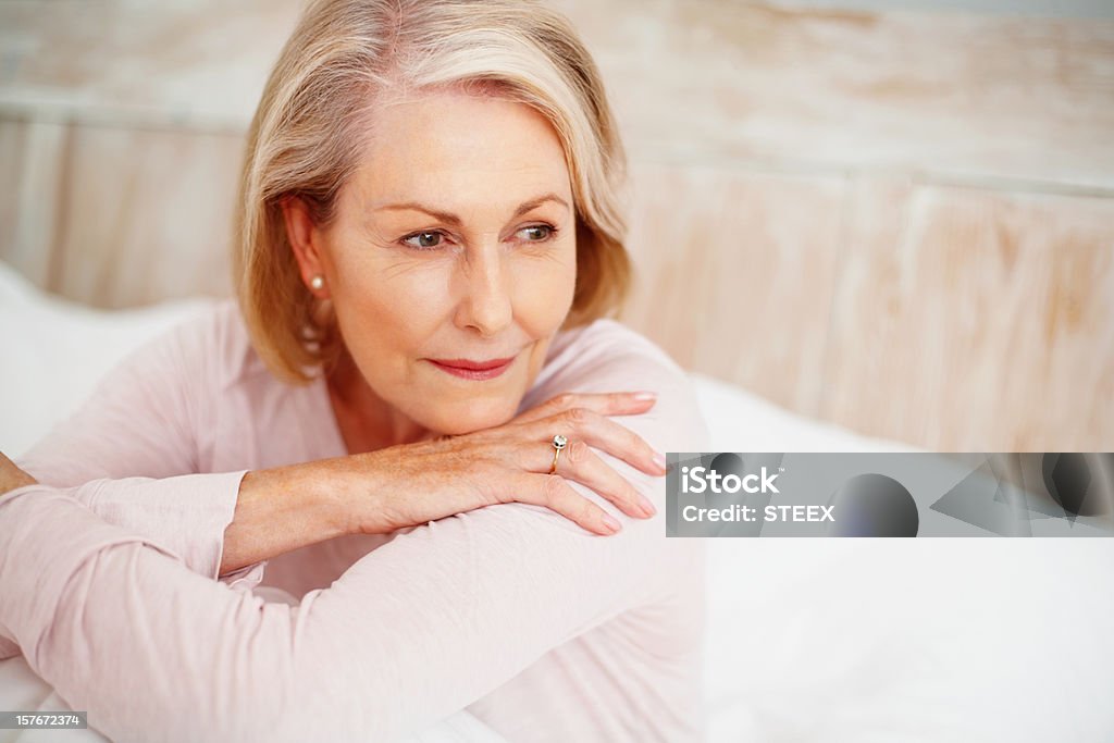 Zrelaksowany dojrzała kobieta w łóżku Patrząc od hotelu - Zbiór zdjęć royalty-free (Kobiety)