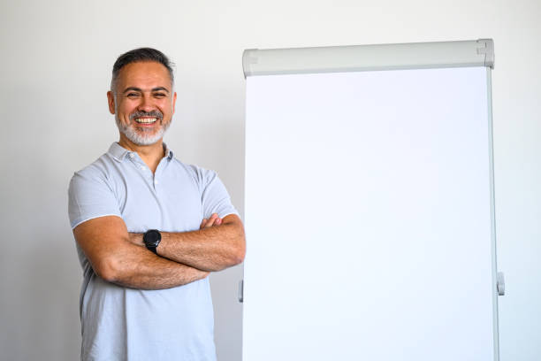 istock Happy smiling mature man presenting something on the Flipchart 1576723847