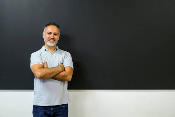 istock Smiling teacher standing at the blackboard 1576723869