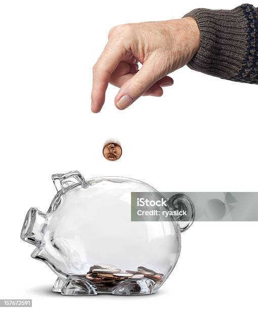 Elderly Hand Dropping Coins Into Almost Empty Piggy Bank Isolated Stock Photo - Download Image Now