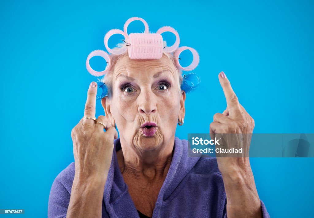 Senior woman with obcene gesture enior woman, 68 years old, with curlers in her hair. Women Stock Photo