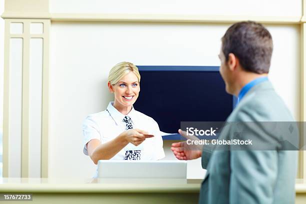 Smiling Receptionist Giving An Airline Ticket To Business Man Stock Photo - Download Image Now