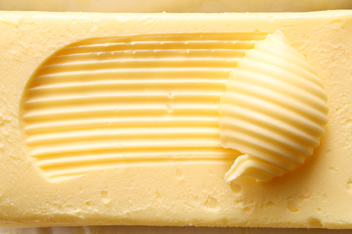 Butter block on wooden board with herbs. Wooden background. Top view.