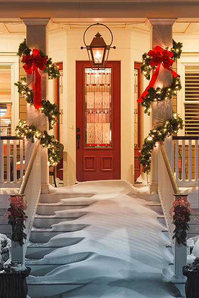 inviting christmas doorway with snow on porch stairs and railing - xmas tree stockfoto's en -beelden