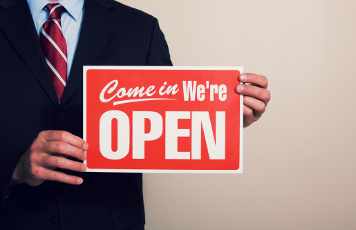 a businessman holding a open for business sign.