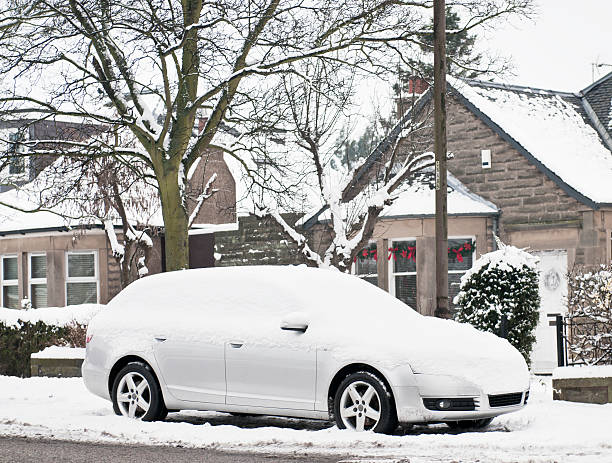 A snow covered car in front of a row of houses on the street in Edinburgh, Scotland.