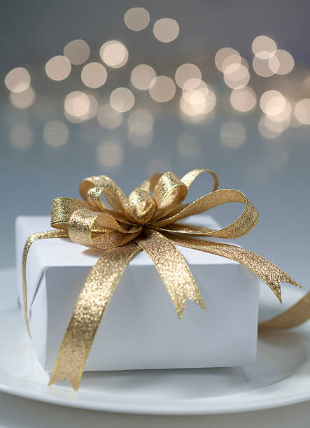 Elegant Christmas gift on a plate with fairy light background. Selective focus.