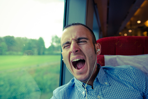 Man Yawning and listening music on the train