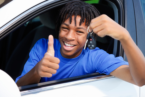 A teenage boy celebrating that he passed his driver's test.