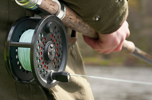 Close up on the rod and reel of a man fishing on the river Spey in the Scottish Highlands.  