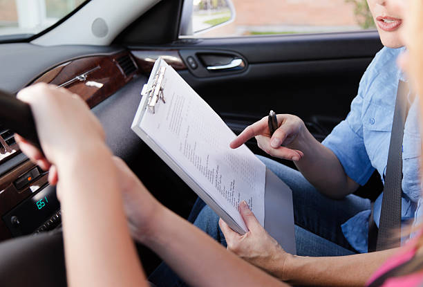 Driving Test A driving instructor holding the driving test checklist inside of the training car. driving test photos stock pictures, royalty-free photos & images