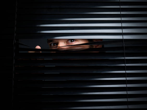 Mysterious Male Peering Out From Opening Behind Blinds