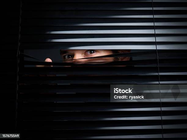 Mysterious Male Peering Out From Opening Behind Blinds Stock Photo - Download Image Now