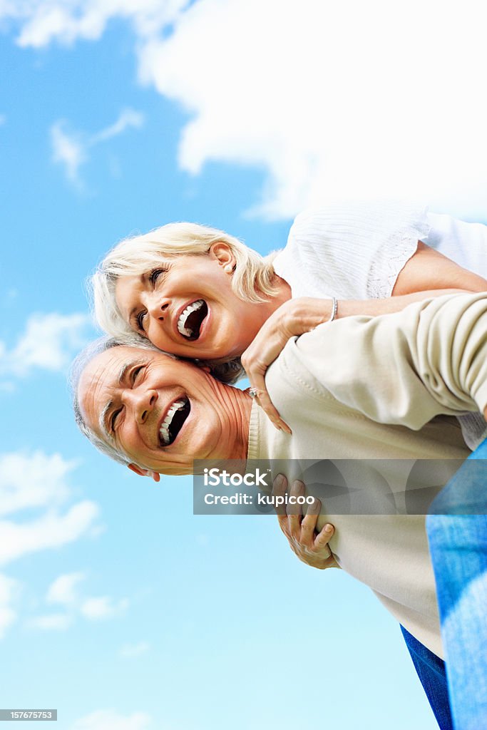 Веселая Молодая пара против неба piggybacking - Стоковые фото 40-49 лет роялти-фри