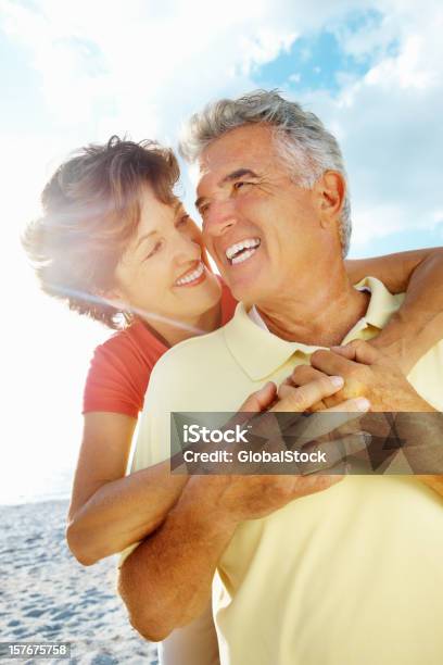 Lächelnd Senior Frau Umarmen Mann Von Hinten Auf Den Strand Stockfoto und mehr Bilder von Paar - Partnerschaft