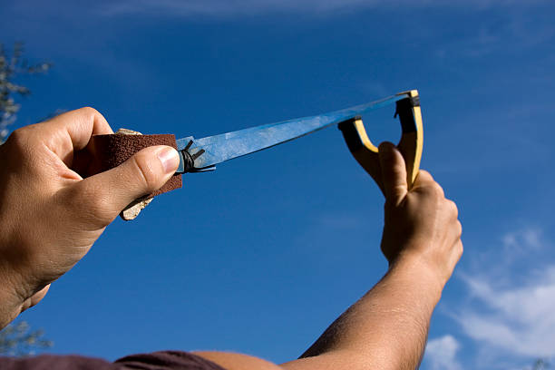 A rock is pulled back in an sling shot pointed to the sky stock photo