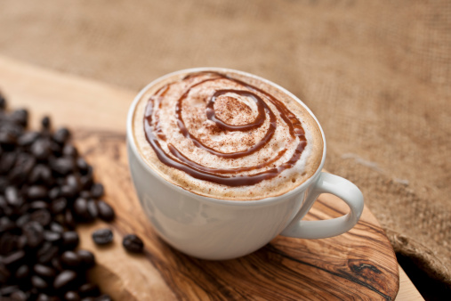 Cappuccino topped with swirls of chocolate sauce.