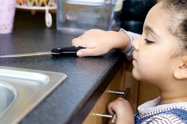 Child Grabbing Kitchen Knife, age 3 years old, Horizontal Royalty free stock photo of 3 years old girl who is attempting to grab kitchen knife. ringlet stock pictures, royalty-free photos & images