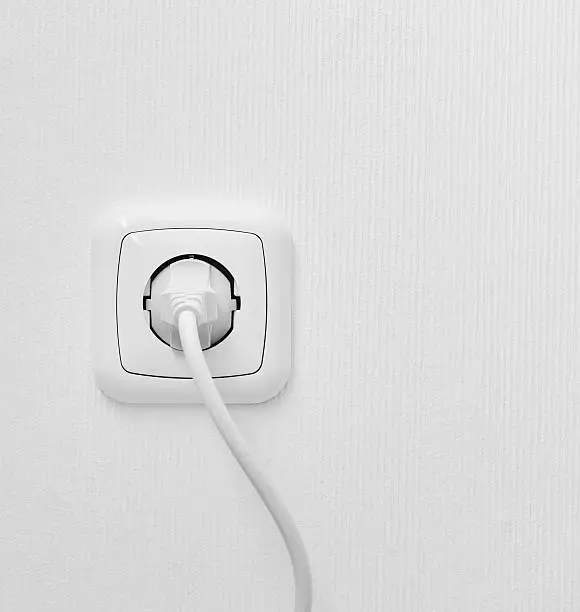 brand new outlet on a white wall with plug and copyspace
