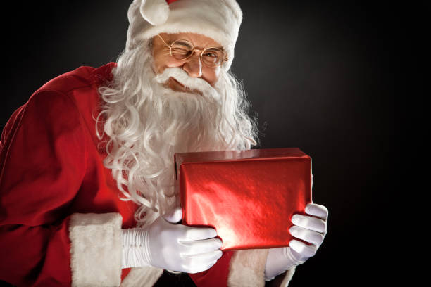 Santa Claus holding a gifts boxs. On dark background 