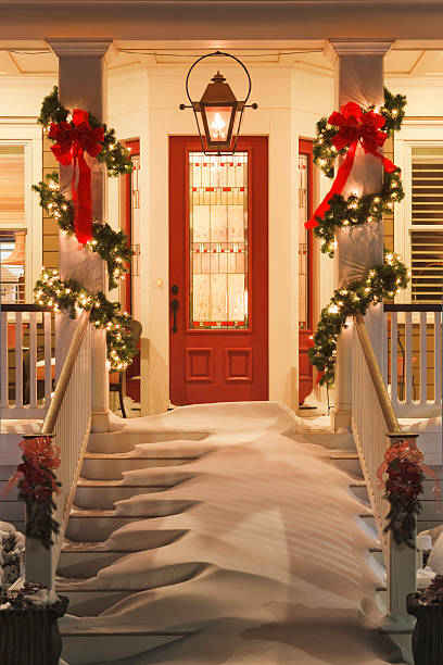 inviting Christmas home doorway with snowy porch at night inviting doorway with snow on porch stairs and railing christmas lights house stock pictures, royalty-free photos & images