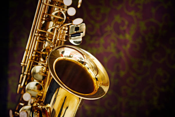 golden saxophone gleams contra un fondo de seda elegantemente decoradas incluyen - light jazz fotografías e imágenes de stock