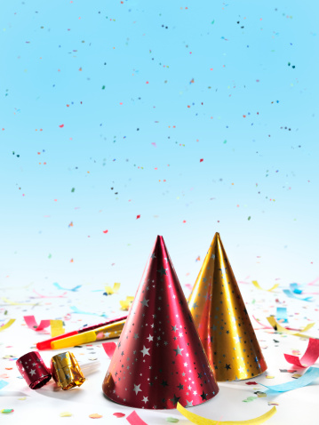 Party decorations: hats, whistles, horns, confetti on gradient blue background. Copy space, studio shot. This picture fits to New Year's, Parties, Birthdays topics.