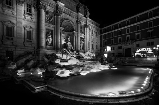 Illuminated Fontana di Trevi in Rome, Italy with an ornate facade of a building in the background