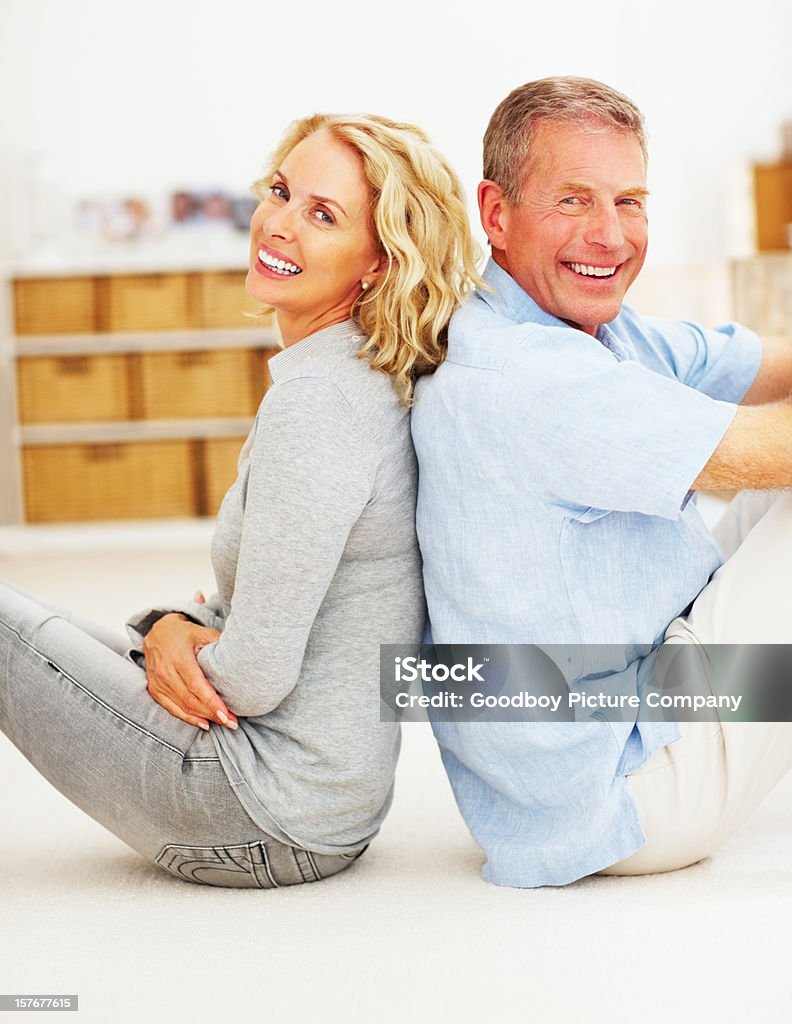Joyeux couple d'âge mûr assis dos à dos à la maison - Photo de Adulte libre de droits