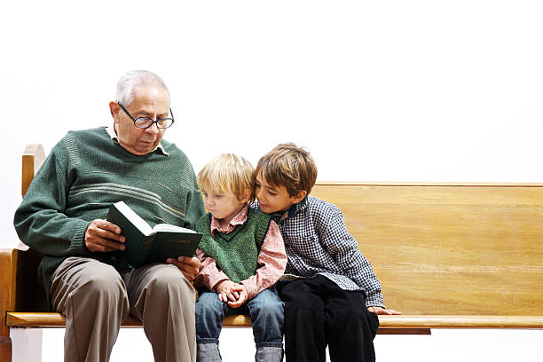 Elderly man reading the Bible to young children  pew stock pictures, royalty-free photos & images