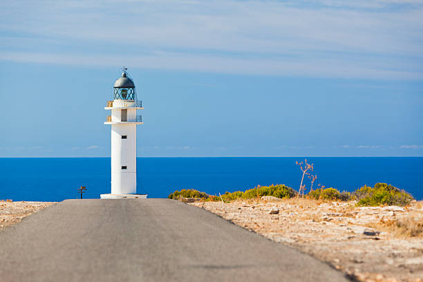 A seagull flies over the landscape of the Cabo de Palos Lighthouse, Mediterranean Sea. Autumn sun in La Manga del Mar Menor. La Manga del Mar Menor, Cartagena, Murcia, Spain - November 16, 2025.