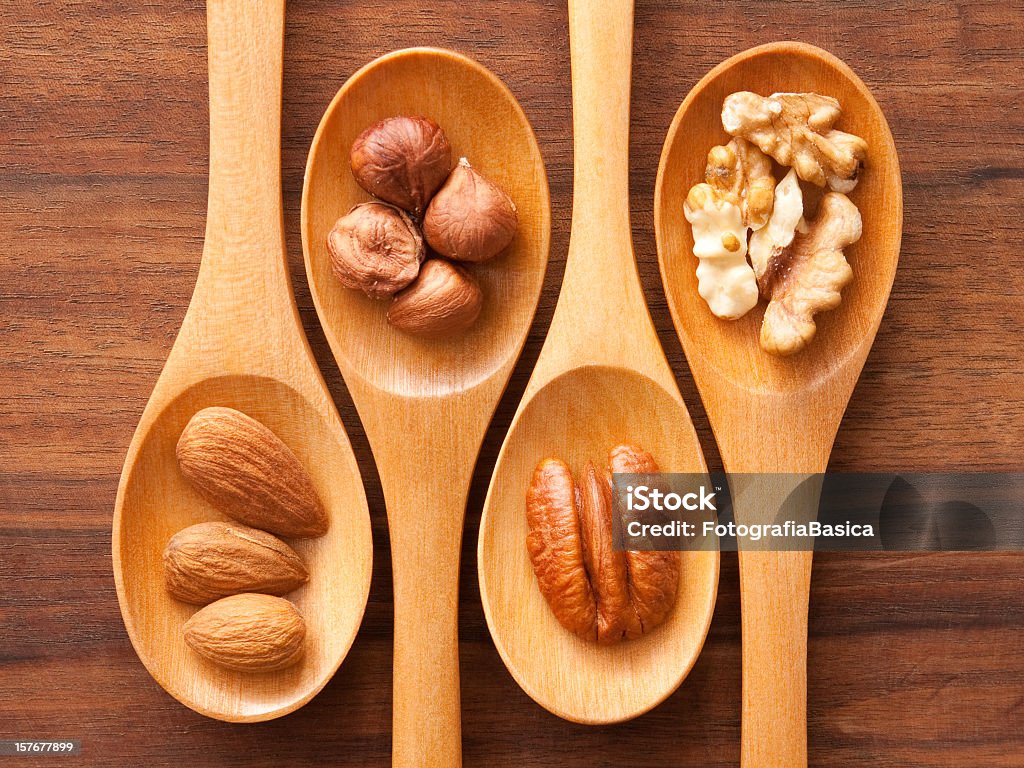 Spoons and nuts Top view of wooden spoon with different types of nuts on them (almonds, hazelnuts, pecan, walnuts) Almond Stock Photo